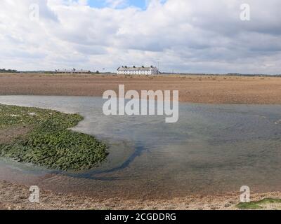 Eine Reihe von ehemaligen Küstenschutzhütten an der Shingle Street, einem isolierten Weiler an den düsteren Schindelbänken von Suffolk. Stockfoto
