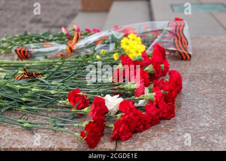 Blumensträuße liegen auf Granitstufen am Fuß Des Denkmals in der Gedenkstätte Sieg während der Feier Des Siegestages Stockfoto