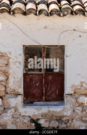 Ein altes zerbrochenes Fenster auf einer enthaupteten Wand auf einem Gebäude auf der griechischen Insel Zante in zakynthos, griechenland Stockfoto