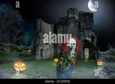 Ein gruseliger Clown in einer gruseligen Umgebung mit Kürbissen und Eine alte Mauer Stockfoto