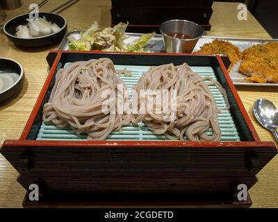 Soba, japanische dünne Nudeln aus Buchweizenmehl. Mori Soba, einfache, gekühlte Buchweizennudeln, serviert auf einem flachen Korb. Serviert mit einer Dip-Sauce. Stockfoto