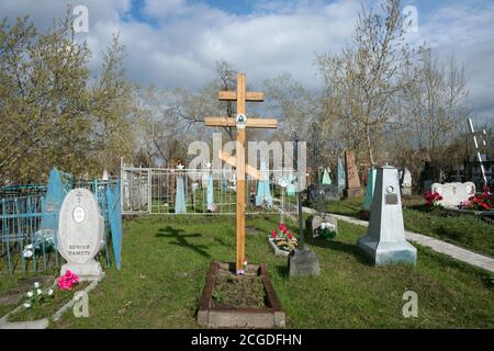 Ein Holzkreuz unter den Gräbern auf dem Troizkoje Friedhof (1842) der Stadt Krasnojarsk, im Frühjahr. Stockfoto