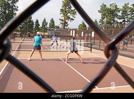 Frauen mittleren Alters spielen Pickleball auf einem Pickleball-Platz in einem Stadtpark in Bend, Oregon Stockfoto