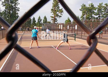 Frauen mittleren Alters spielen Pickleball auf einem Pickleball-Platz in einem Stadtpark in Bend, Oregon Stockfoto