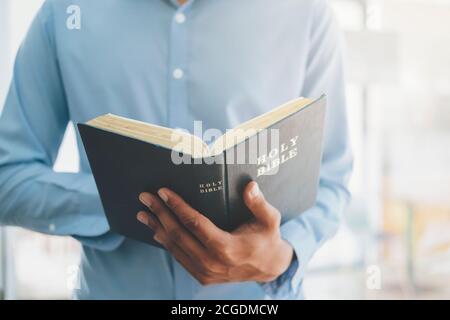 Religion Christentum Konzept. Mann hält und liest die heilige christliche Bibel. Stockfoto