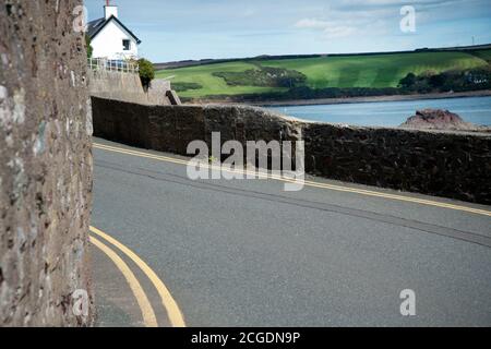 Pembrokeshire, Wales. Dale. Schmale Straße in das Dorf mit doppelten gelben Linien. Stockfoto