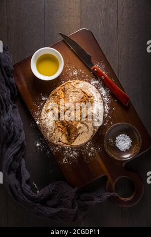 Frisch gebackenes Brot auf Schneidebrett mit Salz und Olivenöl. Draufsicht. Stockfoto