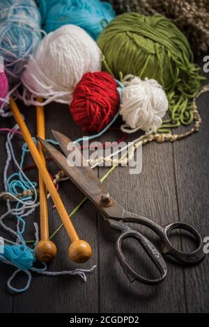 Variation of wool balls for knitting with old scissors in vintage style on wooden background Stockfoto