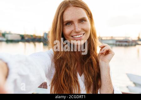 Bild von glücklichen Ingwer Frau lächeln und Selfie-Foto Beim Spazierengehen auf der Promenade Stockfoto