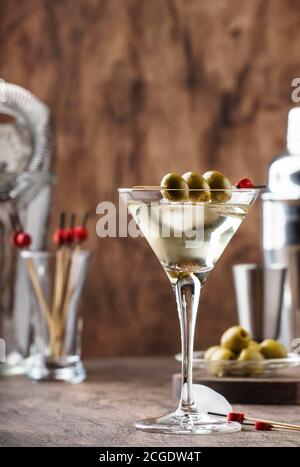 Klassischer Martini-Wodka-Cocktail, mit trockenem Wermut, Wodka und grünen Oliven, Bar-Werkzeuge, Vintage-Holz-Theke, selektiver Fokus Stockfoto