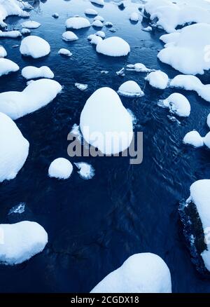 Verschneite Steine auf kleinen Bach im Winter, Finnland Stockfoto