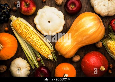 Thanksgiving Hintergrund, Lebensmittel Herbst Ernte Konzept. Rustikaler Tisch mit Äpfeln, Kürbissen, Nüssen, Trauben und Mais auf dunklem Tisch mit Kopierfläche, top vie Stockfoto