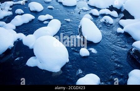 Verschneite Steine auf kleinen Bach im Winter, Finnland Stockfoto