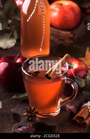 Heißer Apfelmost mit Zimtstangen, Nelken und Anis auf Holzgrund. Traditionelle Herbstgetränke, Wintergetränke und Cocktails Stockfoto