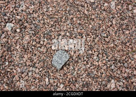 Stein auf einem Hintergrund von grobem Sand, Kieselsteine Nahaufnahme. Hintergrund. Stockfoto