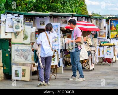 Touristen, die sich links ein Gemälde zum Verkauf angeschaut haben ufer der seine Stockfoto
