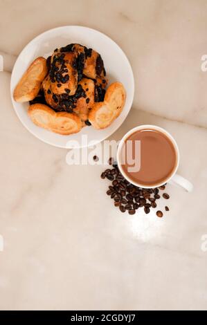 Tasse Kaffee, Bohnen, mit Teller mit Süßigkeiten auf Marmortisch, Ansicht von oben Stockfoto