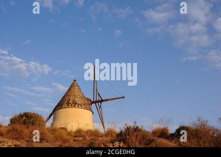 Alte, weiße Windmühle in der Nähe von San Jose. Wunderschöne Landschaft im Naturpark Cabo de Gata, Almeria, Spanien Stockfoto