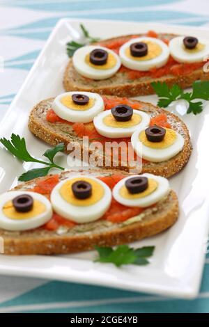 Swedish Open Sandwich mit in Scheiben geschnittenem gekochtem Ei, schwarzen Oliven und Dill auf gewürztem Kabeljau Roggenbrot. Stockfoto