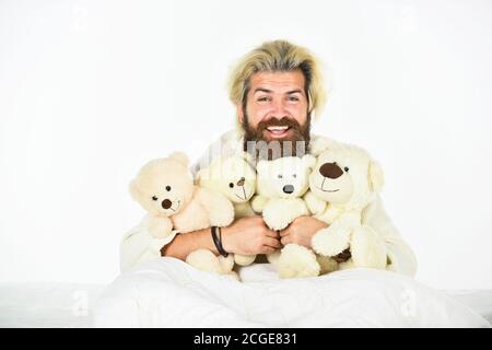 Mann umarmt Spielzeug entspannen im Bett. Bärtige Hipster spielen Spielzeug. Gute Stimmung. Imaginäre Freunde. Bemühen Sie sich, gute Schlafgewohnheiten zu üben. Niedliche Teddybär Spielzeug. Positive Schlafzimmerumgebung. Verspielt und romantisch. Stockfoto