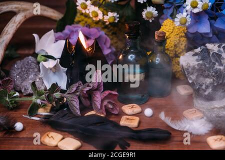 Flasche mit Zaubertrank. Hexerei halloween Konzept mit Tränke, Kräutern und okkulten Geräten. Magisches Stillleben mit Kopierraum auf dunklem Hintergrund. Stockfoto