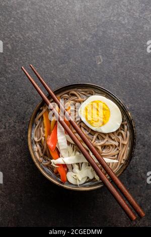 Asiatische Nudelsuppe mit Soba-Nudeln, Gemüse und Ei in einer Schüssel. Draufsicht. Stockfoto