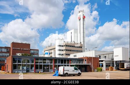 Bürogebäude und Kamin der Jacobs Douwe Egberts Kaffeerösterei unter blauem Himmel mit Wolken. Utrecht, Niederlande. Stockfoto