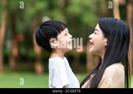 Portrait schöne asiatische Mutter und Sohn lachen sich gegenseitig im Park, niedlich und warm. Stockfoto