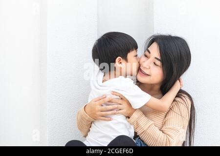 Mutter und Kind umarmten sich und küssten sich gegenseitig die Wangen. Asiatische Familie Mutter und Kind umarmen und duftend, Wangen zusammen, niedlich und warm. Stockfoto