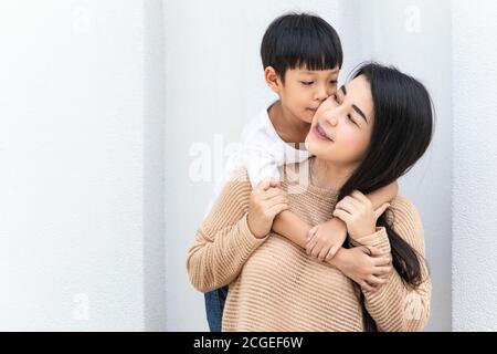 Mutter und Kind umarmten sich und küssten sich gegenseitig die Wangen. Asiatische Familie Mutter und Kind umarmen und duftend, Wangen zusammen, niedlich und warm. Stockfoto