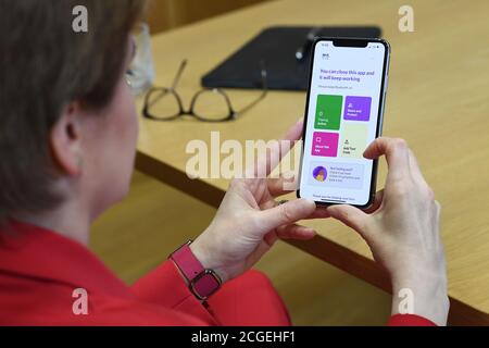 Erste Ministerin Nicola Sturgeon sieht die neue Track-and-Trace-App Covid-19 am Telefon im schottischen Parlament in Edinburgh. Stockfoto