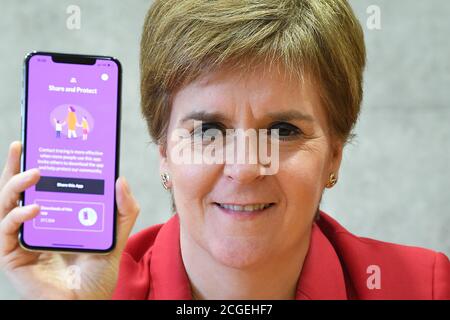Erste Ministerin Nicola Sturgeon sieht die neue Track-and-Trace-App Covid-19 am Telefon im schottischen Parlament in Edinburgh. Stockfoto