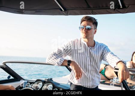 Segeln, Tourismus, Reisen, Business und Personen Konzept - schöner Mann auf Segel yacht Floating in Meer über dem blauen Meer Hintergrund. Stockfoto