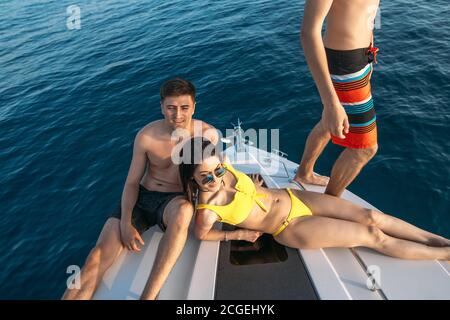 Urlaub auf einem Segelboot. Liebevolles Paar und ihr männlicher Freund verbringen Freizeit in der offenen See. Jungs und Mädchen auf einer Seereise auf einer Yacht. Jung Stockfoto