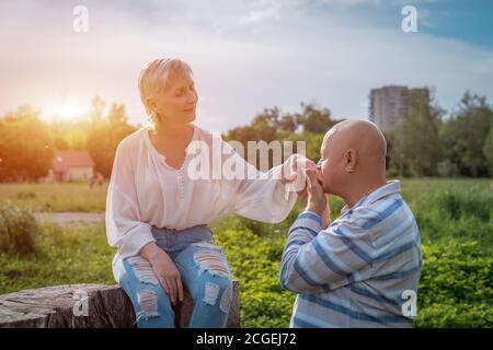 Älterer Mann hält und küsst Frau Hand auf Datum in parken Stockfoto