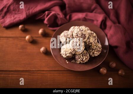 Kakaobälle, Schokolade Trüffel Kuchen an Bord auf Holz Hintergrund Cashewnüsse bestreut Stockfoto