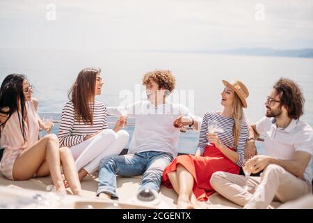 Zwei kaukasischen Männern drei schöne Frauen einladen Vergnügen Yachtcharter Reise auf dem Meer zu den Inseln zu teilen, junge Leute lachen, genießen einen erstaunlichen Blick auf das Meer Stockfoto