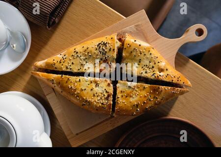 Khachapuri mit Lamm bestreut mit Sesam darauf. Ein Gericht der georgischen Küche. Köstliche khachapuri mit Fleisch mit einer goldbraunen Kruste auf einem Woo Stockfoto