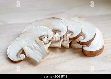 Frische Champignon-Champignons in Scheiben geschnitten auf einem Holzbrett. Geringe Schärfentiefe, Nahaufnahme Stockfoto