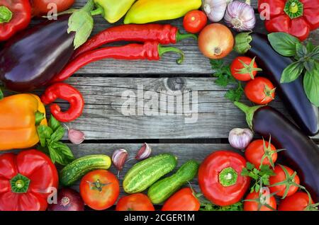 Verschiedene frische Gemüse auf einem rustikalen Holzhintergrund mit Kopierraum in der Mitte, Draufsicht. Das Konzept der gesunden Ernährung. Stockfoto