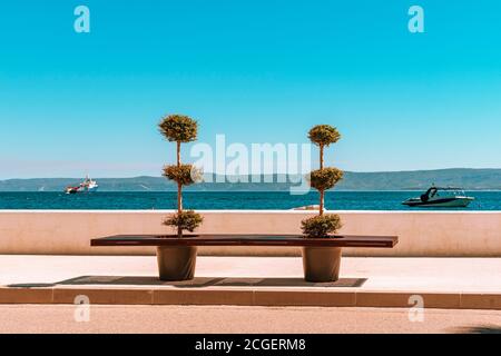 Leere Bank im freien Raum. Schöne Sicht auf das Meer und die Berge in der Ferne. Stockfoto