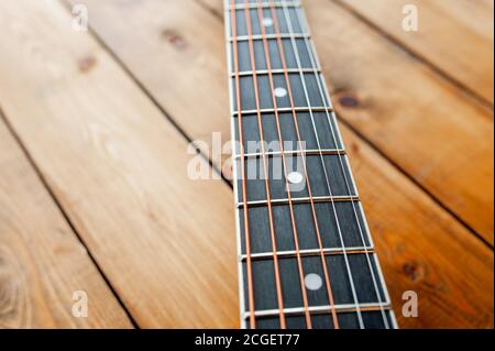 Metallsaiten am Hals einer Akustikgitarre auf Holzbrettern, Nahaufnahme Stockfoto