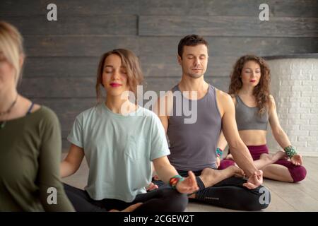 Gruppe von jungen sportlichen Menschen Yoga-Unterricht mit geschlossenen Augen, sitzen in Sukhasana Übung, Easy Seat Pose. Stockfoto