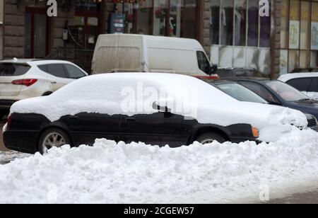 Autos auf einer Seite der Stadt Straße mit Schnee im Winter geparkt. Stockfoto
