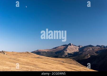 Mond über West Beckwith Berg im späten Nachmittag Licht des Herbstes. Trail Ridge Aussichtspunkt des Longs Peak mit Mond im späten Nachmittagslicht. Stockfoto