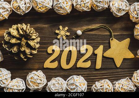 Neujahr 2021. Goldene Zahlen, Dekorationen und eine leuchtende Girlande auf einem dunklen Holztisch. Frohe Weihnachten und Frohes neues Jahr. Nahaufnahme. Draufsicht. Stockfoto