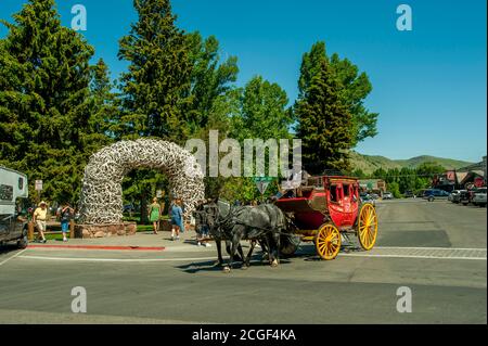 Eine Postkutsche bietet Fahrten für Touristen mit dem Hintergrund der Elche Antler Arche auf dem Stadtplatz, komplett aus lokalen Elchgeweih in Jackso gebaut Stockfoto