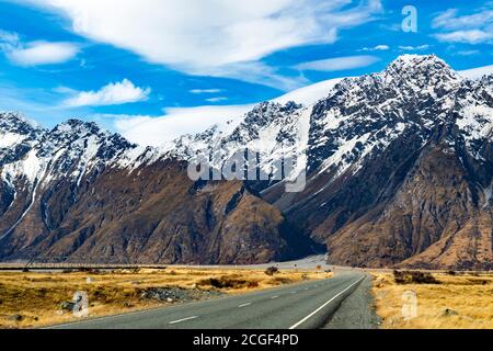 Die Straße direkt in die Berge, felsige Gipfel mit Schnee im Winter und schöne Wolken während des Tages im Nationalpark-Bereich, Mount coo bedeckt Stockfoto