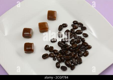 Kaffee harte Bonbons und Kaffeebohnen auf weißem Dessertteller Auf Lavendel Hintergrund Stockfoto