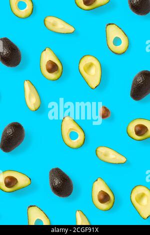 Avocado. Hintergrund aus isolierten Avocado-Stücken auf blauem Hintergrund. Flache Laie aus frischen reifen Avocados und Avacadostücken. Stockfoto